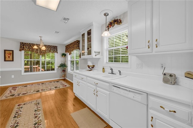 kitchen featuring white dishwasher, a sink, light wood-style flooring, and white cabinetry