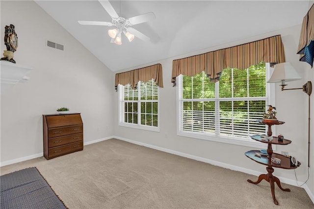 empty room featuring lofted ceiling, light carpet, healthy amount of natural light, a ceiling fan, and baseboards