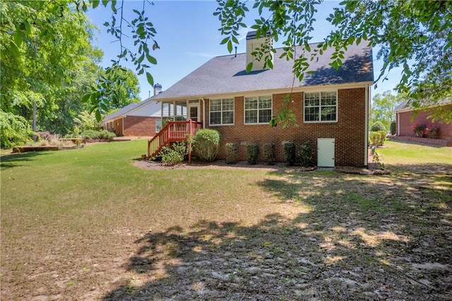 back of property with a yard, a chimney, and brick siding