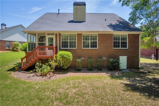 back of property with a lawn, a sunroom, brick siding, stairway, and a chimney