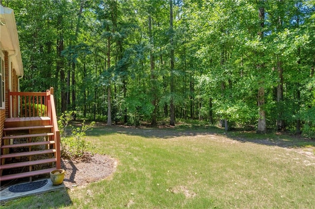 view of grassy yard featuring a wooded view