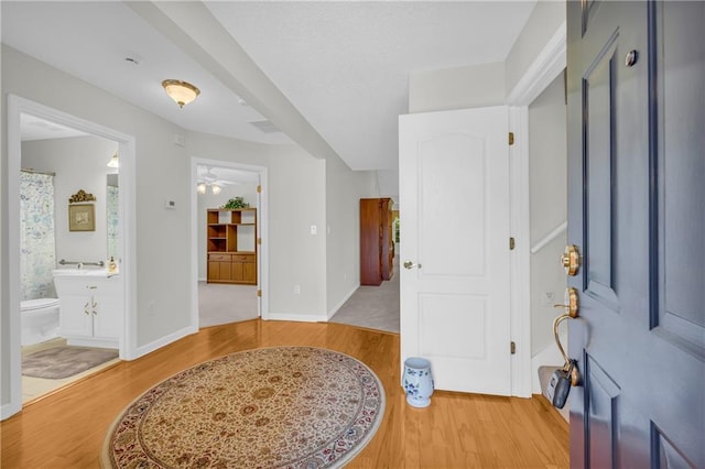 foyer with light wood-type flooring, ceiling fan, and baseboards
