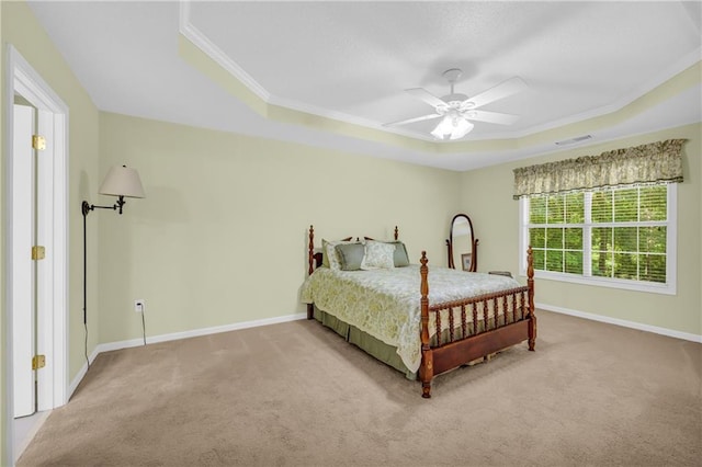 bedroom featuring a tray ceiling, carpet, ornamental molding, baseboards, and a ceiling fan