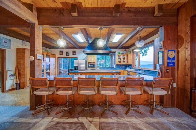 kitchen featuring wood ceiling, a breakfast bar area, beam ceiling, and stainless steel fridge with ice dispenser