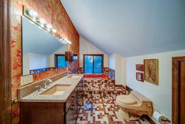 full bathroom featuring lofted ceiling, a garden tub, double vanity, and a sink