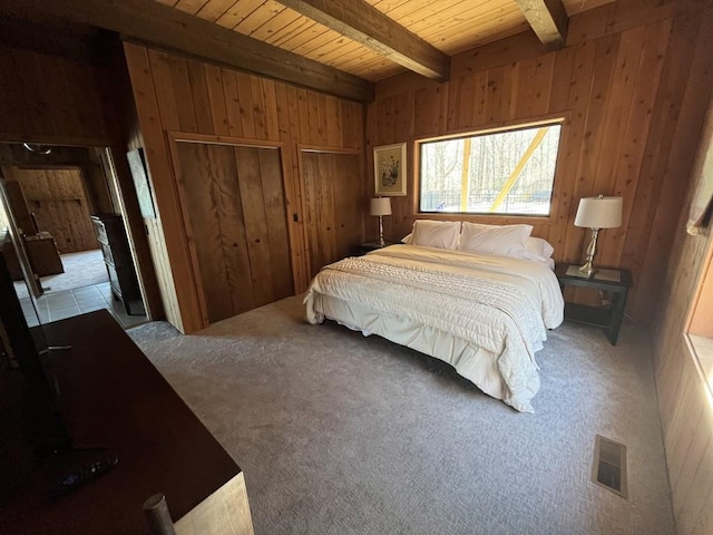 bedroom with beamed ceiling, wood walls, visible vents, and light colored carpet