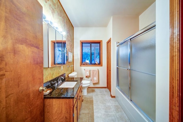 full bathroom with bath / shower combo with glass door, baseboards, toilet, tile patterned flooring, and vanity