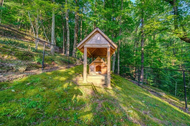 view of outdoor structure featuring a fireplace and fence