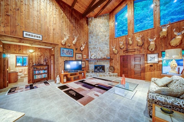 living area featuring beamed ceiling, a fireplace, wood ceiling, and wooden walls