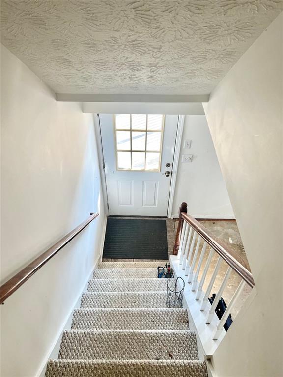 stairs featuring a textured ceiling