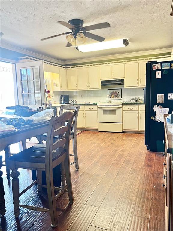 kitchen with refrigerator, light hardwood / wood-style flooring, ornamental molding, electric stove, and range hood