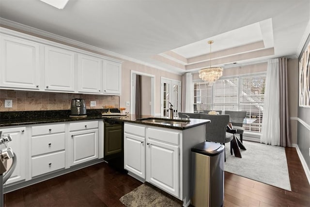 kitchen featuring pendant lighting, black dishwasher, sink, white cabinets, and a raised ceiling