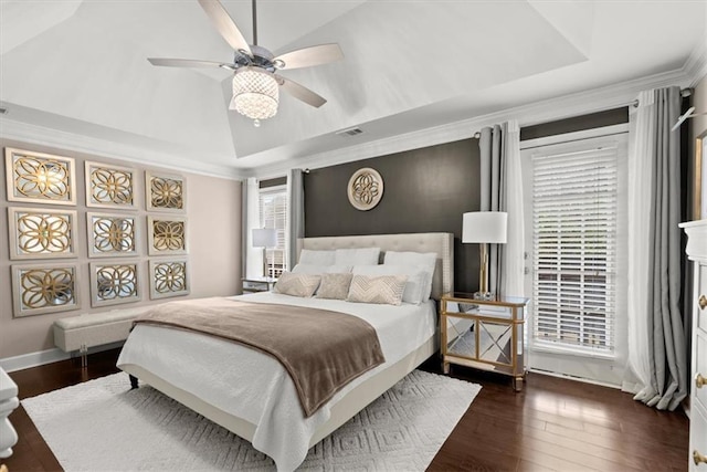 bedroom with dark hardwood / wood-style flooring, vaulted ceiling, and a raised ceiling