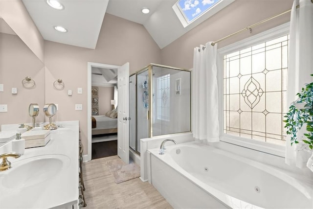 bathroom with shower with separate bathtub, plenty of natural light, vaulted ceiling with skylight, and vanity