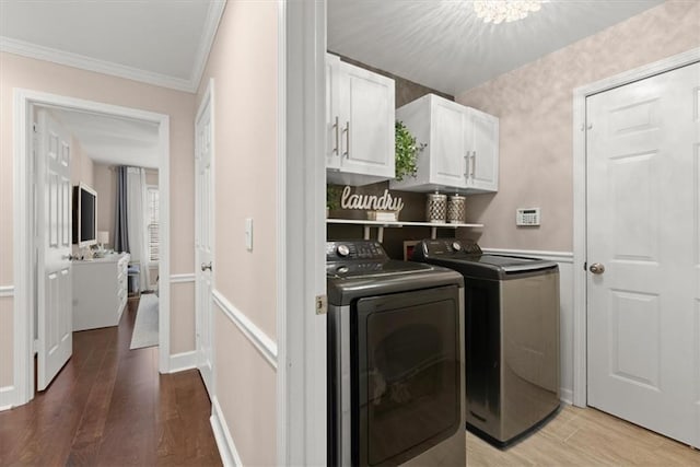 laundry room with cabinets, ornamental molding, hardwood / wood-style flooring, and washer and dryer