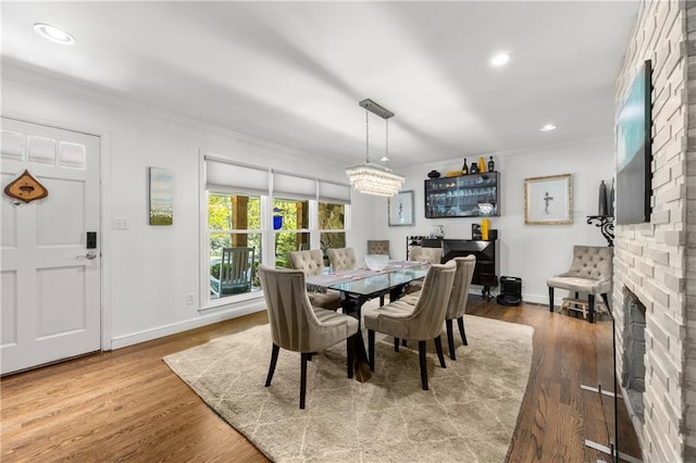 dining room featuring a fireplace, hardwood / wood-style flooring, and crown molding