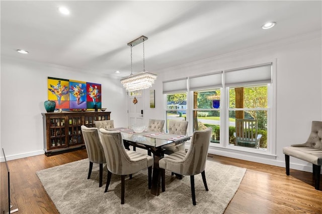 dining space with hardwood / wood-style flooring, crown molding, and a chandelier