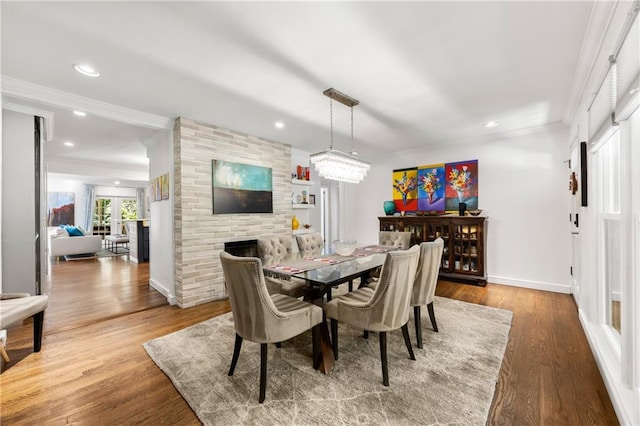 dining area featuring a large fireplace, wood-type flooring, french doors, and ornamental molding