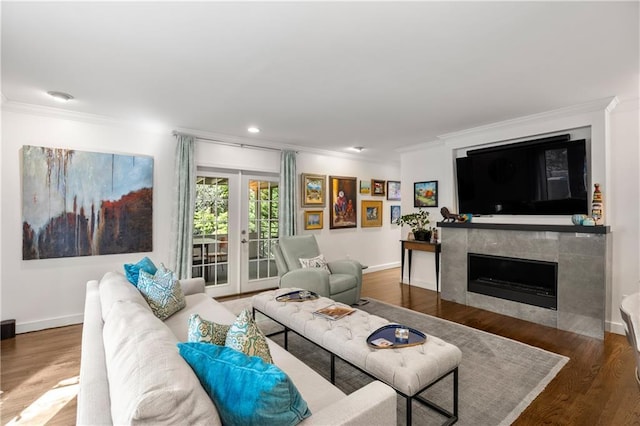 living room with a tile fireplace, crown molding, french doors, and dark hardwood / wood-style floors