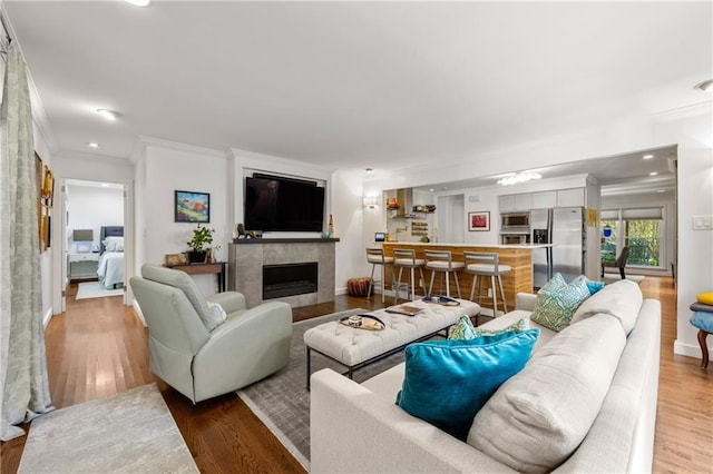 living room featuring a tile fireplace, hardwood / wood-style floors, and crown molding