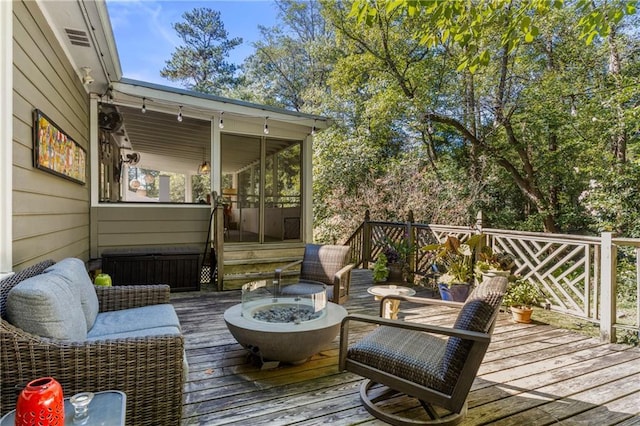 deck featuring radiator heating unit, an outdoor fire pit, and a sunroom