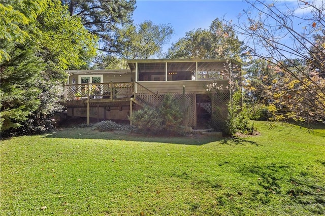 rear view of house with a sunroom, a yard, and a deck