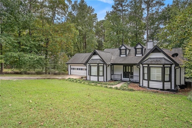 view of front facade with a garage, a chimney, a porch, and a front yard