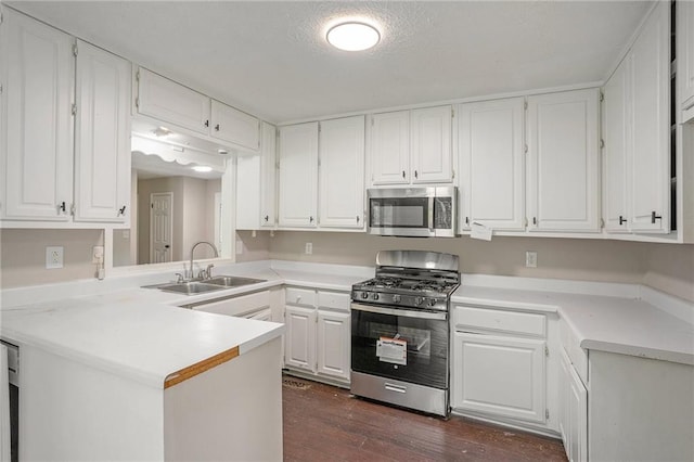 kitchen with light countertops, appliances with stainless steel finishes, dark wood-type flooring, white cabinetry, and a sink