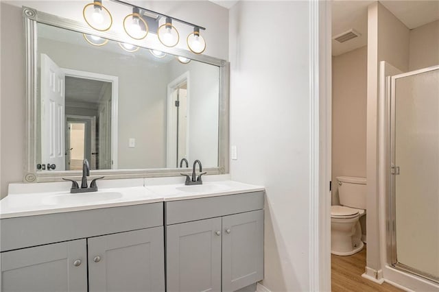 bathroom featuring a sink, a shower stall, toilet, and double vanity