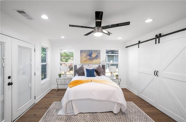 bedroom with ceiling fan, a closet, a barn door, and dark hardwood / wood-style floors