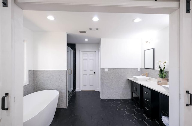 bathroom with tile patterned flooring, vanity, tile walls, and independent shower and bath