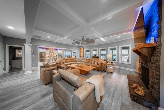 living room featuring a fireplace, coffered ceiling, ceiling fan, beam ceiling, and light hardwood / wood-style flooring