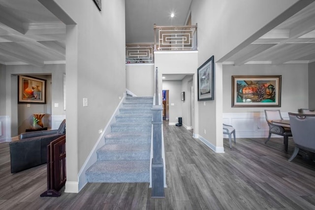 stairs with coffered ceiling, beam ceiling, wood-type flooring, and ornamental molding