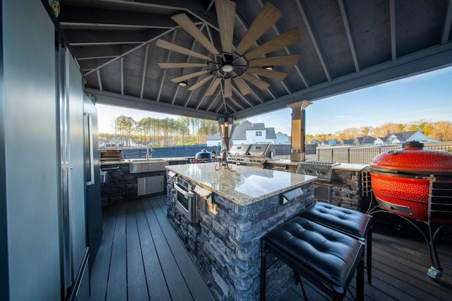 deck with area for grilling, sink, ceiling fan, and a grill