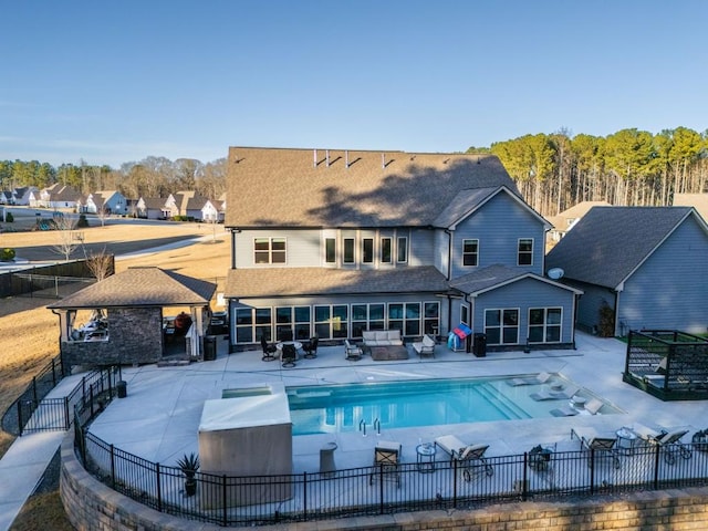 rear view of property with a fenced in pool, a patio, and an outdoor hangout area