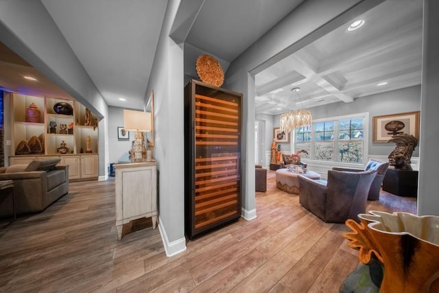 bar with beverage cooler, coffered ceiling, beam ceiling, and light wood-type flooring