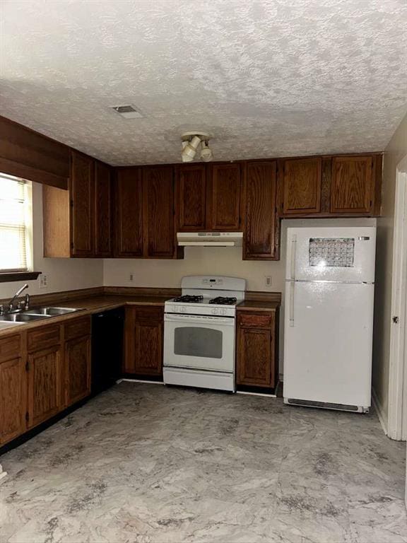 kitchen featuring white appliances, a textured ceiling, under cabinet range hood, visible vents, and a sink