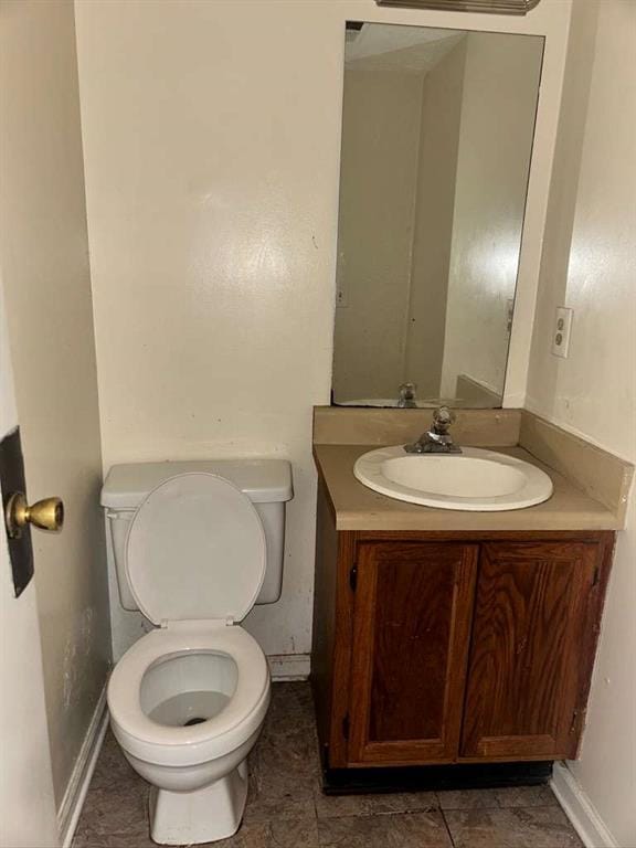 half bath featuring toilet, vanity, and baseboards