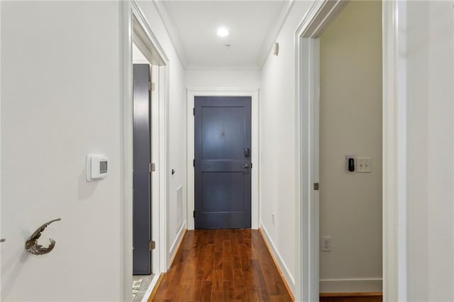 corridor with dark wood-style floors, ornamental molding, and baseboards
