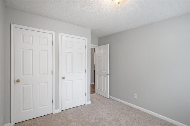 unfurnished bedroom with light colored carpet and a textured ceiling