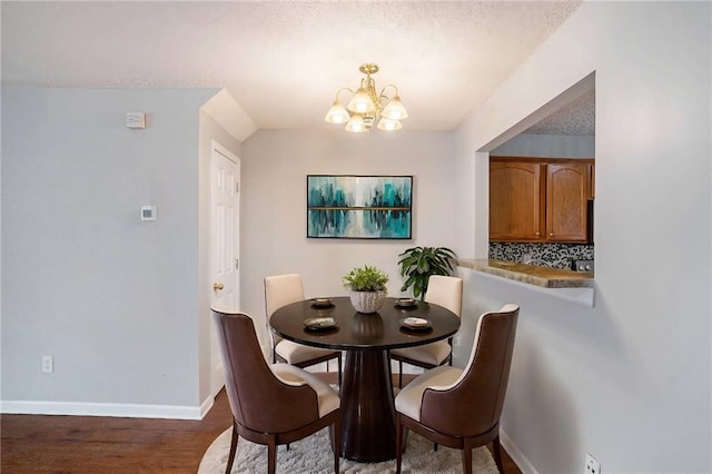 dining area with a notable chandelier, a textured ceiling, and dark hardwood / wood-style flooring