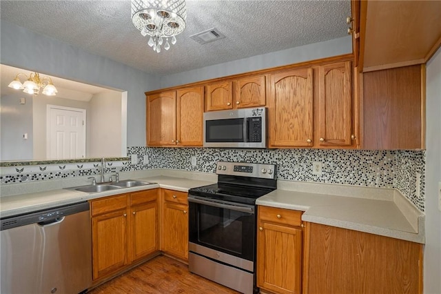 kitchen with an inviting chandelier, appliances with stainless steel finishes, sink, and a textured ceiling