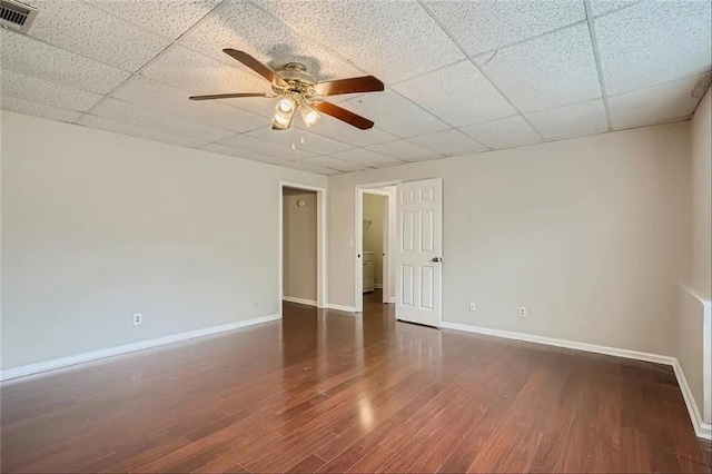 spare room with a paneled ceiling, ceiling fan, and dark hardwood / wood-style flooring