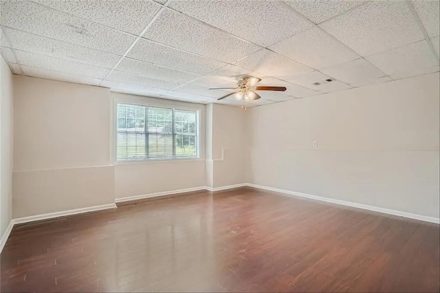 empty room featuring a paneled ceiling, ceiling fan, and dark wood-type flooring