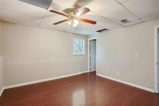 spare room featuring a drop ceiling, ceiling fan, and dark wood-type flooring