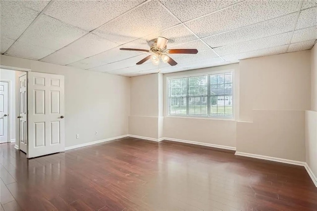 spare room with a drop ceiling, ceiling fan, and dark hardwood / wood-style floors