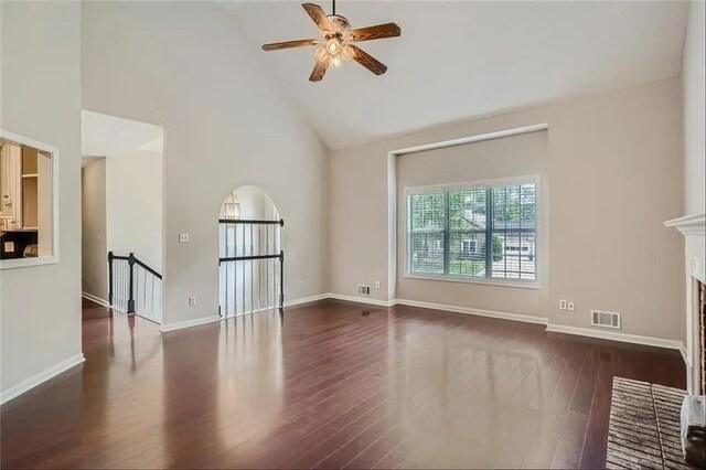 unfurnished living room with a brick fireplace, high vaulted ceiling, ceiling fan, and dark wood-type flooring