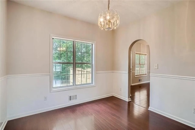 unfurnished room featuring a notable chandelier and dark hardwood / wood-style floors