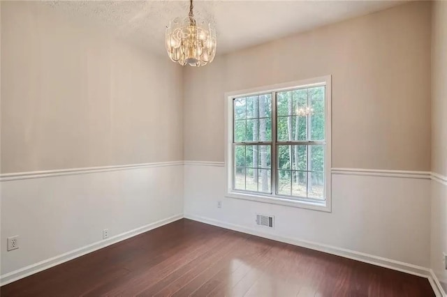 unfurnished room with dark wood-type flooring and a chandelier
