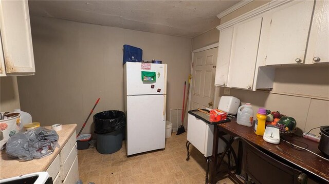 kitchen featuring stove, white cabinetry, and white fridge